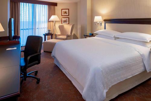 a hotel room with a large bed and a chair at Sheraton Houston Brookhollow Hotel in Houston