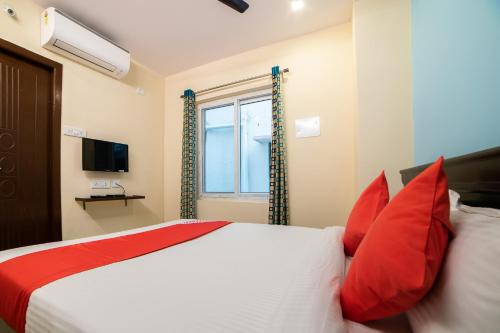 a bedroom with a bed with red pillows and a window at Hotel O White Ridge in Hyderabad
