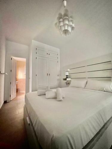 a bedroom with a large white bed with a chandelier at Home Boutique Cervantes in Málaga