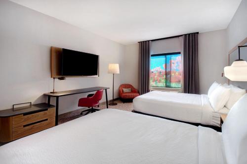 a hotel room with two beds and a desk and a television at Fairfield Inn & Suites Lancaster Palmdale in Lancaster