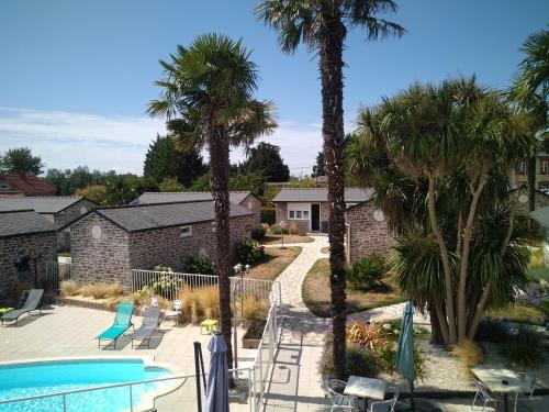 un complexe avec une piscine et des palmiers dans l'établissement Hôtel les 13 Assiettes, à Le Val-Saint-Père