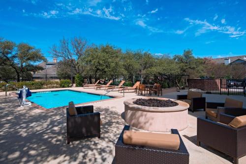 une cour avec une piscine, des chaises et un foyer extérieur dans l'établissement Fairfield Inn and Suites by Marriott Austin Northwest/Research Blvd, à Austin