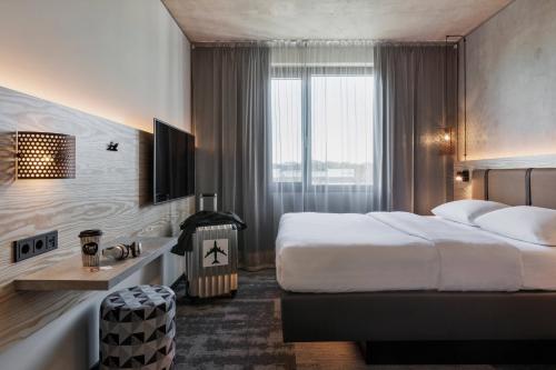 um quarto de hotel com uma cama grande e uma janela em Moxy Frankfurt Airport Kelsterbach em Kelsterbach