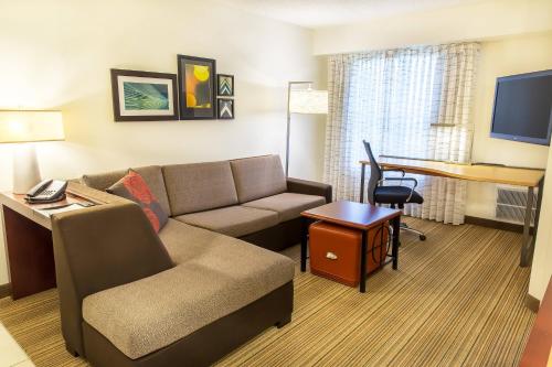 Residence Inn Sioux Falls في شلالات سيوكس: غرفة معيشة مع أريكة ومكتب في غرفة الفندق