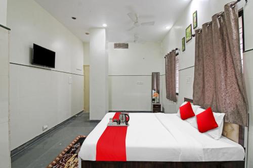 a bedroom with a bed with red pillows and a tv at Hotel Sunshine Inn in Nagpur