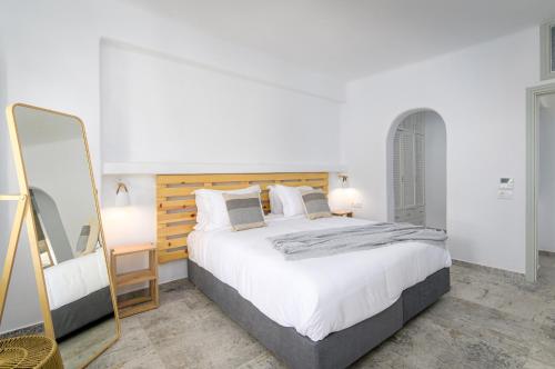 1 dormitorio con 1 cama grande y espejo en Geminos Complex Villas en Kamari