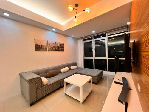 een woonkamer met een bank en een tafel bij The Pearl Interior Designed 1 BR Unit Burgos Circle BGC in Manilla