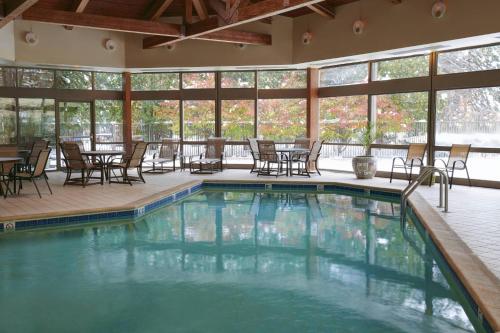 a swimming pool with chairs and tables and windows at Detroit Marriott Livonia in Livonia