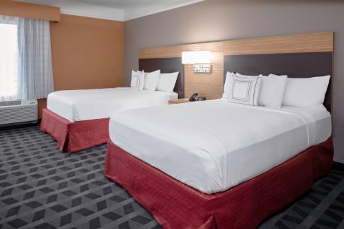 two beds in a hotel room with white sheets at TownePlace Suites by Marriott Gainesville in Gainesville