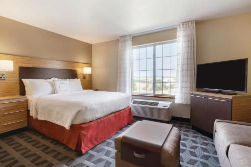 a hotel room with a bed and a flat screen tv at TownePlace Suites by Marriott Boulder Broomfield/Interlocken in Broomfield