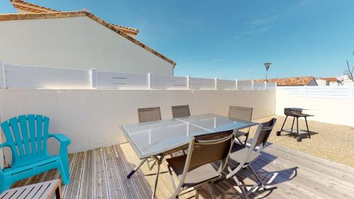 un patio avec une table et des chaises sur une terrasse dans l'établissement Le Repos de la Mer 900 m plage, à Saint-Gilles-Croix-de-Vie