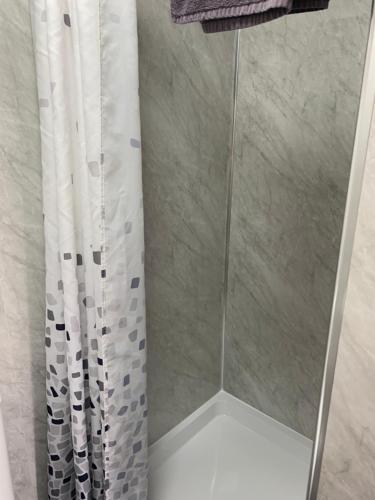 a shower with a white shower curtain in a bathroom at The Woodleigh family hotel in Blackpool