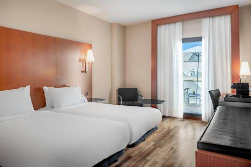 um quarto de hotel com uma cama, uma secretária e uma janela em AC Hotel Badajoz by Marriott em Badajós