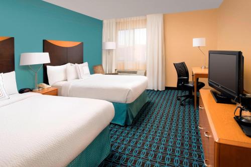 a hotel room with two beds and a flat screen tv at Fairfield Inn & Suites by Marriott Albuquerque Airport in Albuquerque