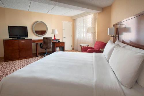 um quarto de hotel com uma grande cama branca e uma secretária em Long Island Marriott Hotel em Uniondale