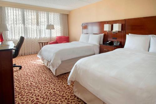 a hotel room with two beds and a desk at Long Island Marriott Hotel in Uniondale