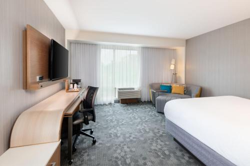 a hotel room with a bed and a desk at Courtyard by Marriott Atlanta Alpharetta/Avalon Area in Alpharetta
