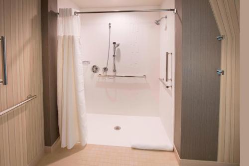 a bathroom with a shower with a white tub at Courtyard by Marriott Atlanta Alpharetta/Avalon Area in Alpharetta