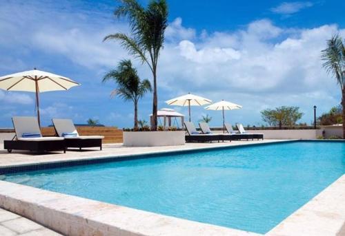 a swimming pool with chairs and umbrellas at Hotel La Vista Azul in Turtle Cove