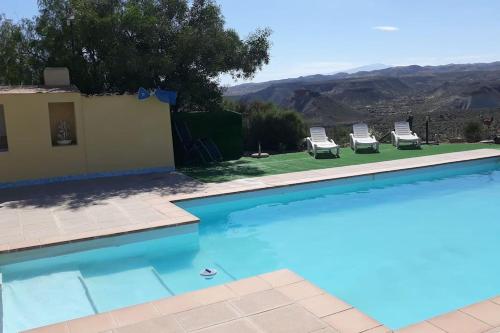 a pool with chairs and a view of the mountains at Desert Escapes in Tabernas