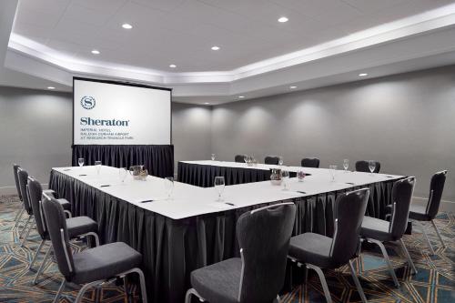 a conference room with a table and chairs and a screen at Sheraton Imperial Hotel Raleigh-Durham Airport at Research Triangle Park in Durham