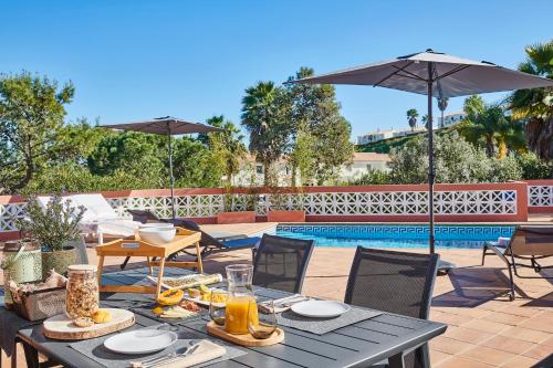 a table with food and an umbrella next to a pool at Panorama Castro Marim - Deluxe Villa With Pool in Castro Marim