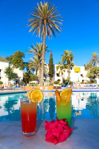 two drinks on a table next to a swimming pool at Caribbean Village Agador - All inclusive in Agadir