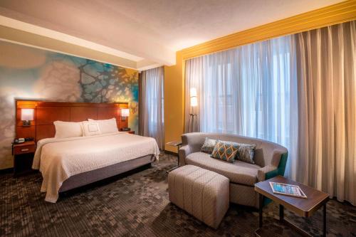 a hotel room with a bed and a chair at Courtyard by Marriott Tulsa Downtown in Tulsa