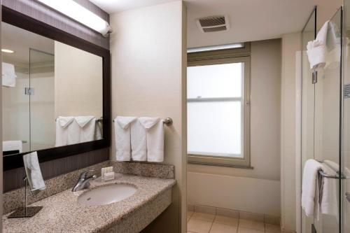 a bathroom with a sink and a mirror and a window at Courtyard by Marriott Tulsa Downtown in Tulsa