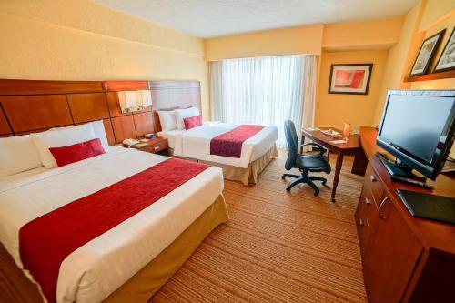 a hotel room with two beds and a flat screen tv at Courtyard by Marriott Puebla Las Animas in Puebla