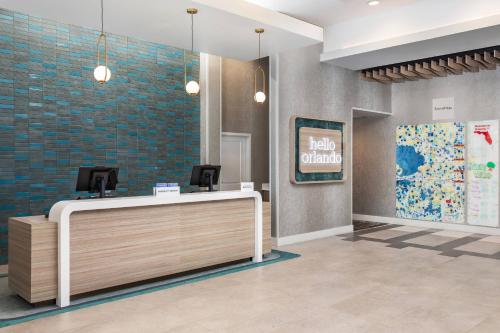 a lobby with a reception desk and a hello ordinary sign at TownePlace Suites By Marriott Orlando Southwest Near Universal in Orlando