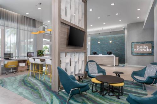 a lobby with chairs and a table and a tv at TownePlace Suites By Marriott Orlando Southwest Near Universal in Orlando