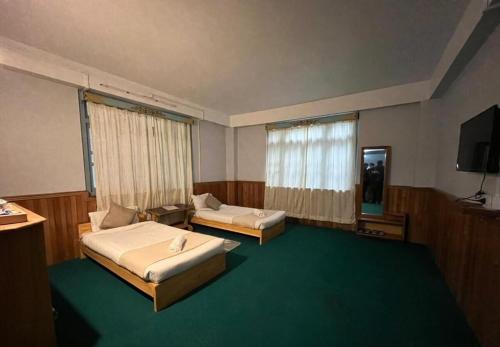a bedroom with two beds and a flat screen tv at Mount Khang Hotel in Lachen