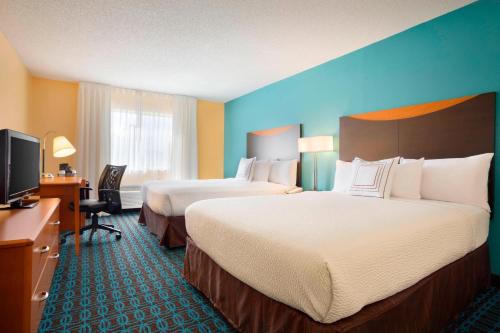 a hotel room with two beds and a flat screen tv at Fairfield Inn & Suites by Marriott Dallas Plano in Plano