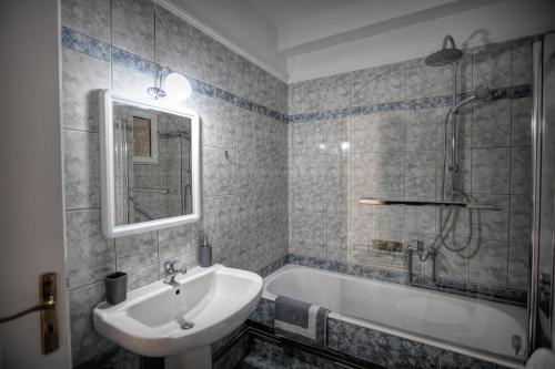 La salle de bains est pourvue d'un lavabo, d'une baignoire et d'un miroir. dans l'établissement Meteora Sky House, à Kalambaka
