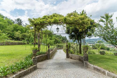 uma entrada para um jardim com um arco e uma passagem em Quinta das Pirâmides - Morgada de Romariz em Vila Nova de Famalicão