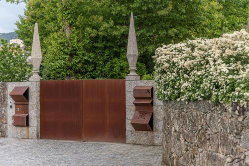 a wooden gate with flowers on a stone wall at Quinta das Piramides in Vila Nova de Famalicão