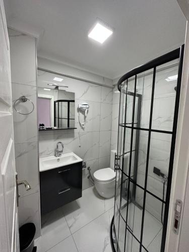 a white bathroom with a toilet and a sink at Vesta Butik Otel in Edremit