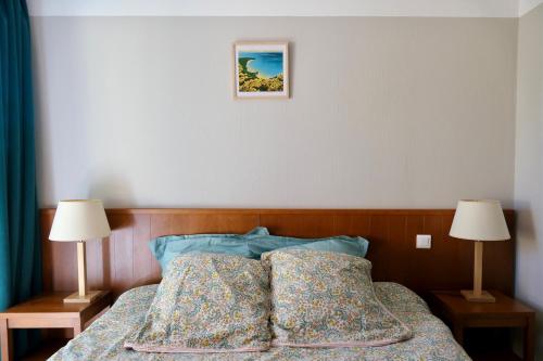 - un lit avec deux oreillers dans une chambre avec deux lampes dans l'établissement Apt Les Grands Pins, entre Forêt, Lac et Océan, à Carcans