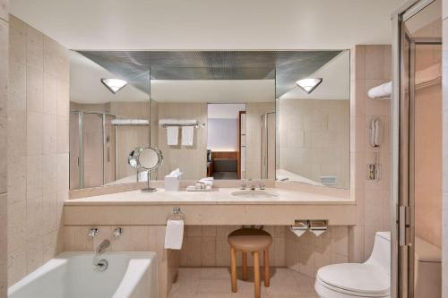 a bathroom with a sink and a toilet and a mirror at Metropolitan Hotel Vancouver in Vancouver