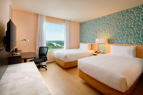 ein Hotelzimmer mit 2 Betten, einem Schreibtisch und einem Fenster in der Unterkunft Fairfield Inn & Suites by Marriott Villahermosa Tabasco in Villahermosa