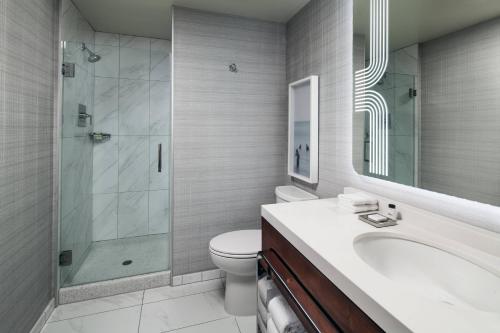 a bathroom with a shower and a toilet and a sink at Sheraton Grand Los Angeles in Los Angeles