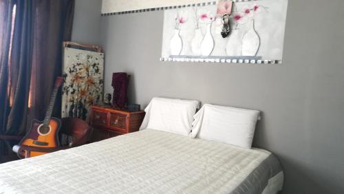 a bedroom with a bed with a guitar and a picture on the wall at Lonehill in Sandton