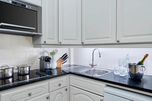 a white kitchen with a sink and a microwave at Grand Residences by Marriott - Mayfair-London in London