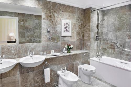 a bathroom with two sinks a toilet and a bath tub at Grand Residences by Marriott - Mayfair-London in London