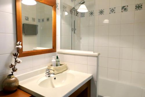 a bathroom with a sink and a mirror and a tub at Appartement Les Grands Pins, entre Lac et Océan in Carcans