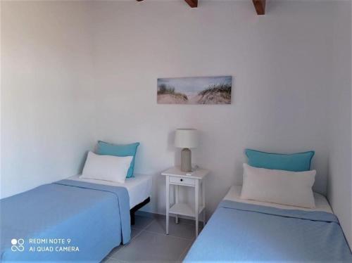 a room with two beds and a small table at Villa Perla Nou in Binibeca