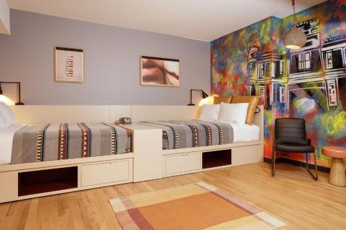 2 Betten in einem Zimmer mit Wandgemälde in der Unterkunft Moxy Richmond Downtown in Richmond