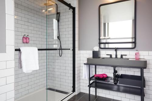 a bathroom with a shower and a sink and a mirror at Moxy Richmond Downtown in Richmond