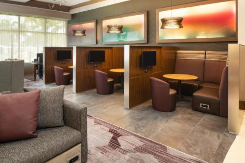 a waiting room with a couch and tables and chairs at Courtyard by Marriott Miami Airport in Miami